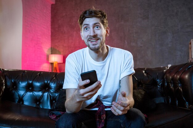 Jeune homme fan regardant un match de football à la télévision célébrant g