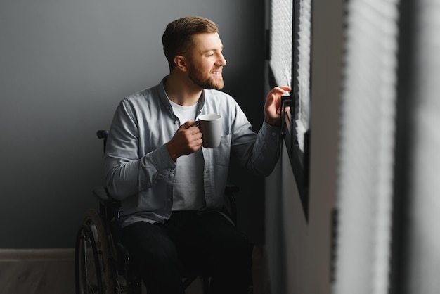 Jeune homme en fauteuil roulant près de la fenêtre à l'intérieur Espace pour le texte