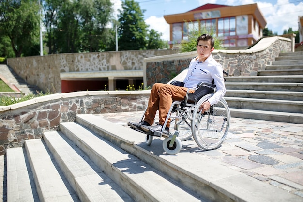Un jeune homme en fauteuil roulant qui ne peut pas descendre les escaliers.