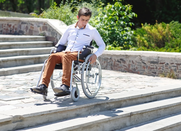 Un jeune homme en fauteuil roulant qui ne peut pas descendre les escaliers.