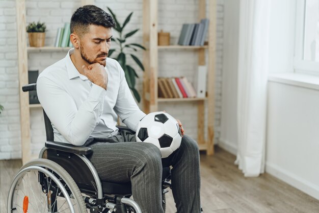 Jeune homme en fauteuil roulant tenant un ballon de football