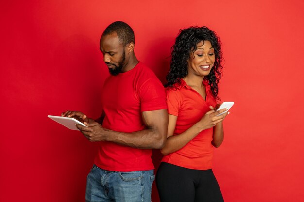 Jeune homme et femme afro-américain émotionnel sur fond rouge