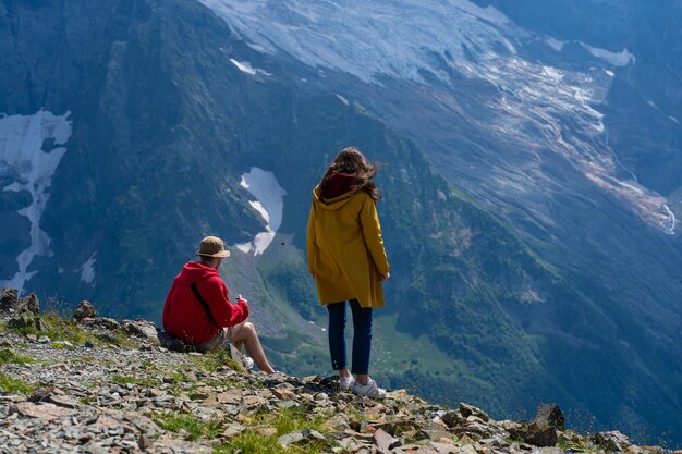 Jeune homme et femme au bord de la montagne bénéficiant d'une belle vue dans la région montagneuse Homme assis sur un rocher et femme debout, ils regardent le paysage de montagne