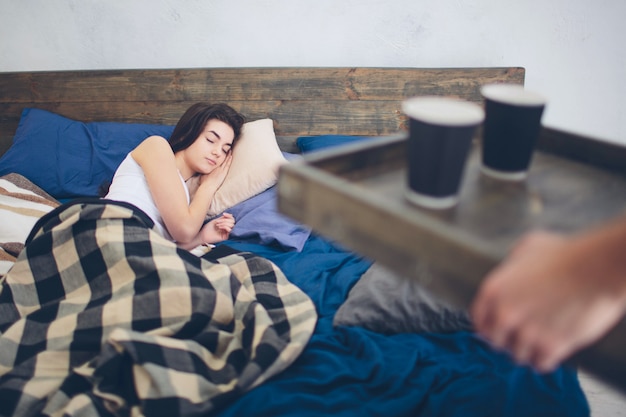 Un jeune homme et une femme boivent du café le matin au lit. Matin romantique à la maison