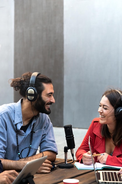 Jeune homme et femme caucasiens enregistrant un podcast Streaming en ligne à l'aide d'un ordinateur portable Image verticale Espace de copie Technologie et concept de médias sociaux