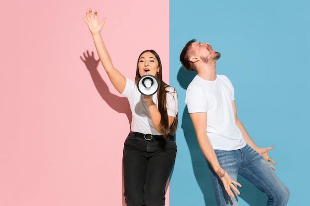 Jeune homme et femme émotifs sur le mur rose et bleu