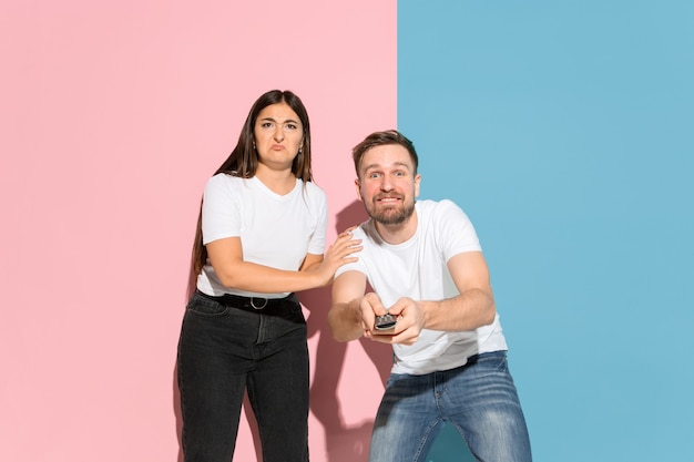 Jeune homme et femme émotifs sur le mur rose et bleu