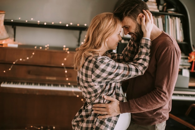 Jeune homme et femme enceinte, étreindre dans la chambre