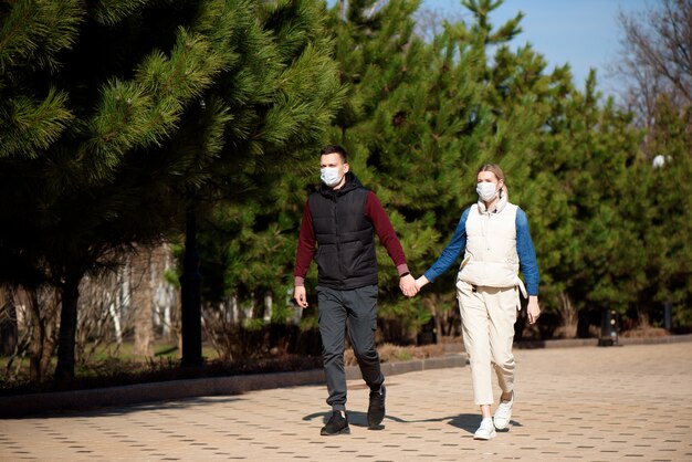 Jeune homme et femme européens en masque médical jetable de protection marchant à l'extérieur peur de dangereux NCoV 2019 grippe coronavirus muté et se propageant en Chine