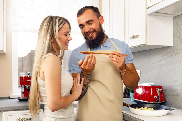 Jeune homme et femme faisant cuire des aliments dans la cuisine ensemble couple heureux préparant des aliments