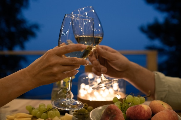 Jeune homme et femme grillant sur une table servie lors d'un dîner romantique