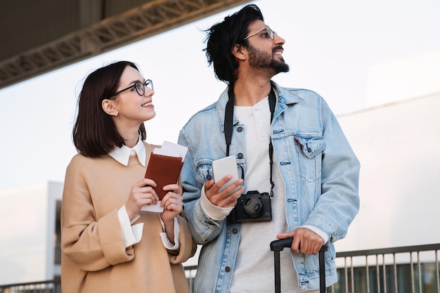 Un jeune homme et une femme internationaux souriants dans des vêtements décontractés et des lunettes regardent le ciel à l'espace libre dans