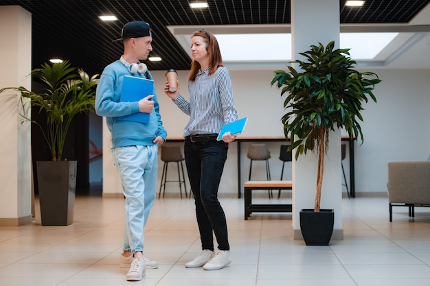 Un jeune homme et une femme modernes et à la mode discutent d'un projet commun au bureau