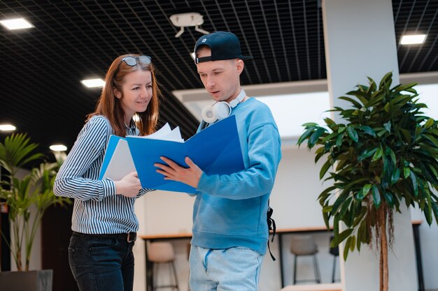 Un jeune homme et une femme modernes et à la mode discutent d'un projet commun au bureau