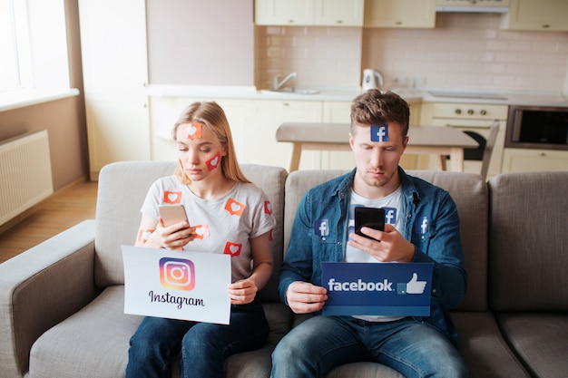 Un jeune homme et une femme ont une dépendance aux médias sociaux. Assis sur le canapé et regardant les téléphones. Concentré.