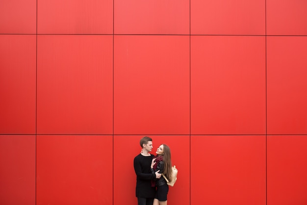 Jeune homme et femme en passion, émotion, dans la rue avec en toile de fond le mur rouge. Mode