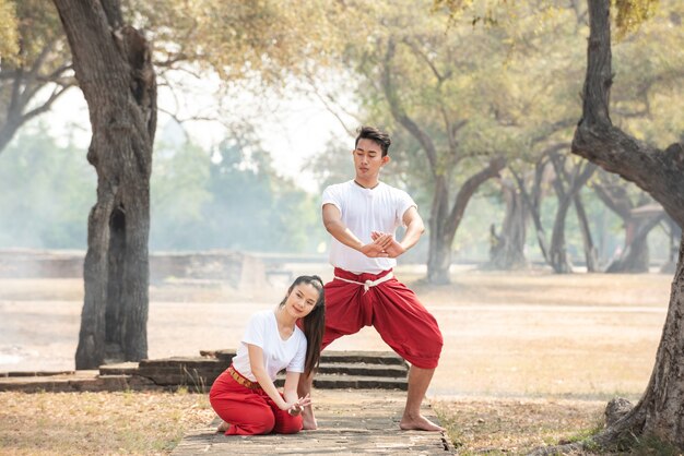 Jeune homme et femme pratiquant une danse traditionnelle thaïlandaise