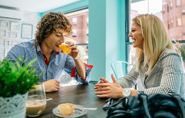 Jeune homme et femme prenant son petit déjeuner dans un café