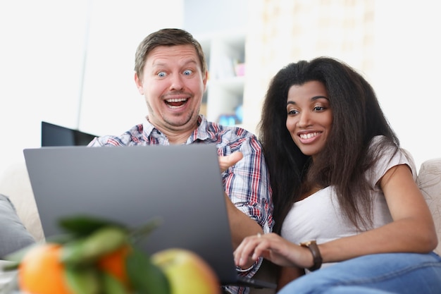 Jeune homme et femme sont assis devant un écran d'ordinateur portable et sourient