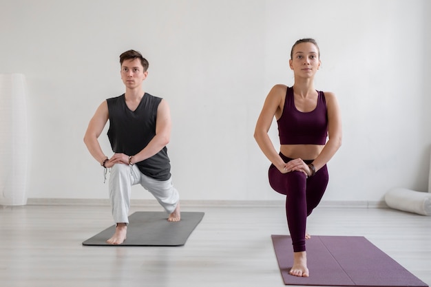 Jeune homme et femme spirituels pratiquant le yoga à l'intérieur