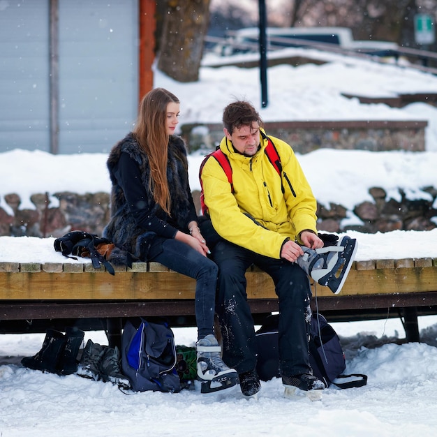 Jeune homme et fille mettant des patins et assis sur le banc à Trakai, Lituanie.