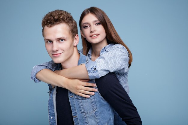 Un jeune homme et une fille en tenue denim sur fond bleu. Jupe, chemise, short et gilet