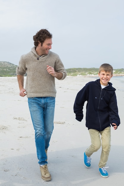 Jeune homme et fils, faire du jogging sur la plage