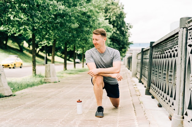 Jeune homme fitness runner étirant les jambes avant l'exercice courir à l'extérieur dans la rue urbaine de la ville en bonne santé