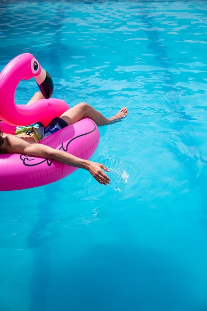 Jeune homme sur un flotteur dans la piscine