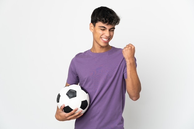 Jeune homme sur fond blanc isolé avec ballon de football célébrant une victoire