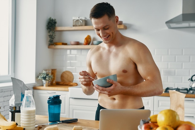 Photo un jeune homme en forme apprécie une nourriture saine alors qu'il se tient à la cuisine