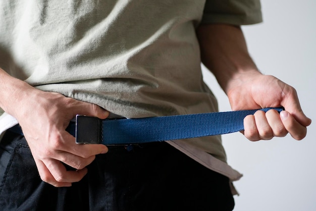 Un jeune homme en forme serre la ceinture du pantalon