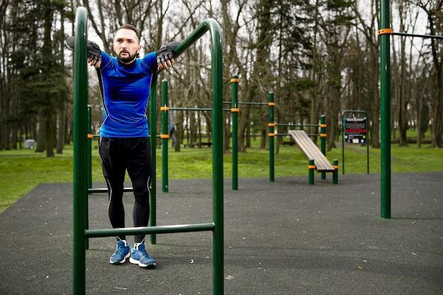 Jeune homme fort se prépare à s'entraîner sur un terrain de sport en été dans la ville