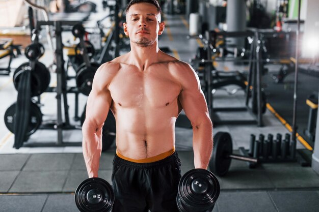 Jeune homme fort sportif en vêtements noirs ont une journée d'entraînement dans la salle de gym