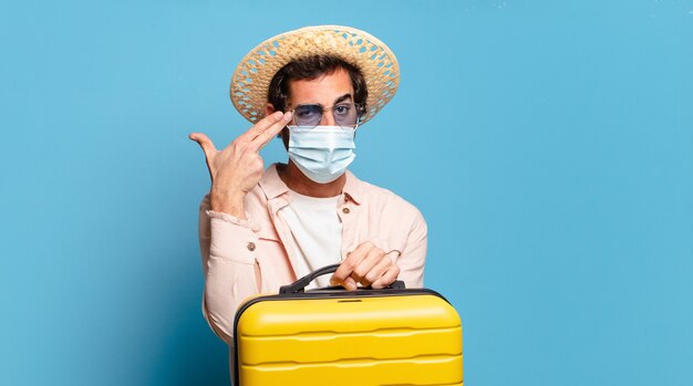 Jeune homme fou barbu avec un masque de covid. concept de voyage.