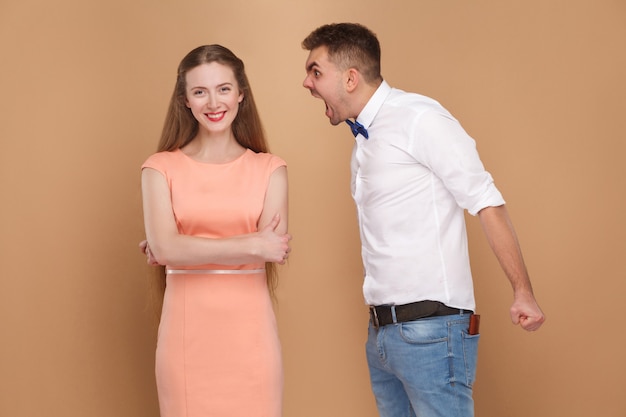 Jeune homme fou en chemise blanche debout et criant à la femme