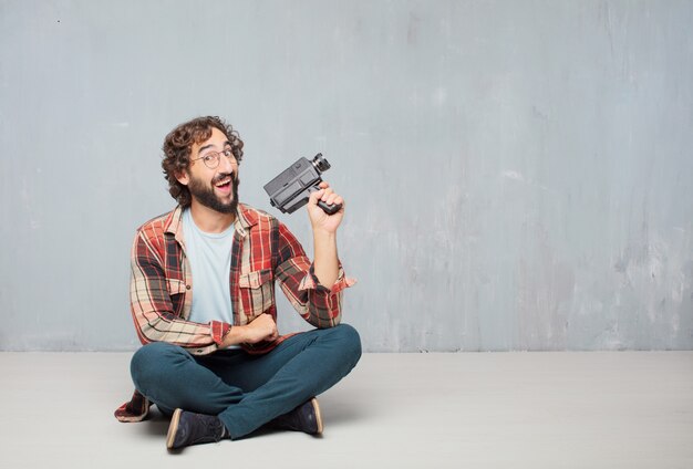 Jeune homme fou fou imbécile pose avec une caméra de cinéma vintage