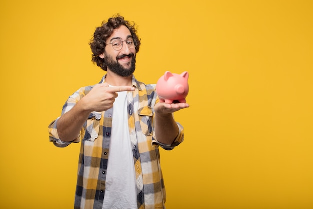 Jeune homme fou fou imbécile pose avec une tirelire. concep d&#39;épargne