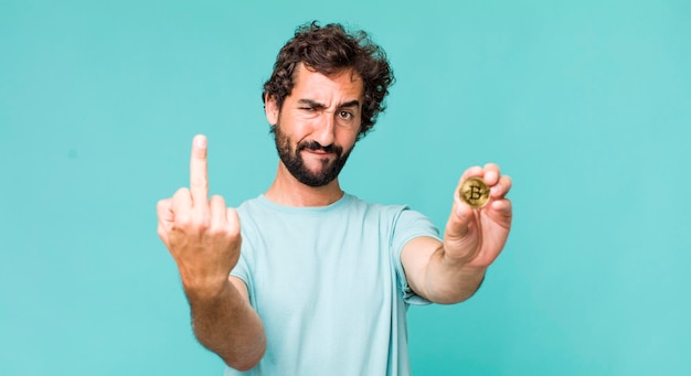 Jeune homme fou hispanique adulte avec une pièce de monnaie bitcoin