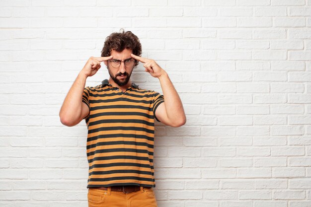 Jeune homme fou ou idiot, gesticulant et exprimant des émotions sur fond de mur de briques