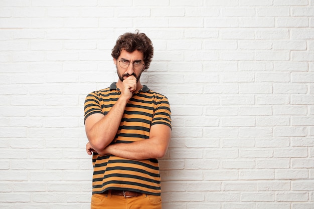 Jeune homme fou ou idiot, gesticulant et exprimant des émotions sur fond de mur de briques