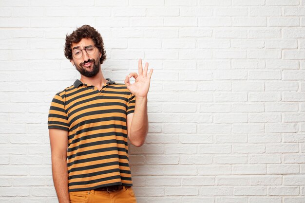 Jeune homme fou ou idiot, gesticulant et exprimant des émotions sur fond de mur de briques