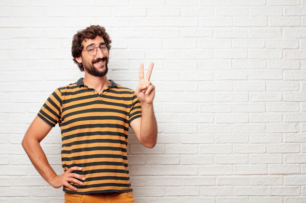 Jeune homme fou ou idiot, gesticulant et exprimant des émotions sur fond de mur de briques