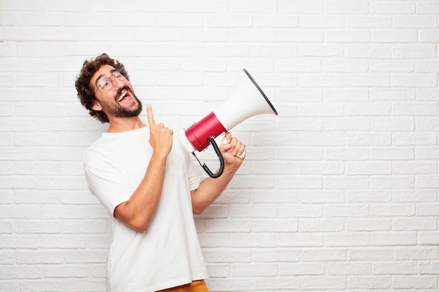 Jeune homme fou avec un mégaphone contre le mur de briques.