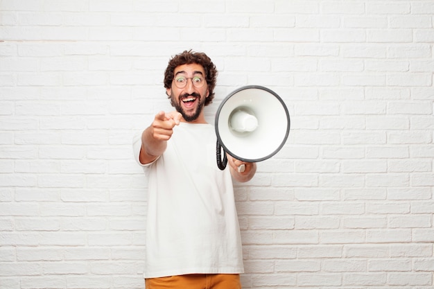 Jeune homme fou avec un mégaphone contre le mur de briques.