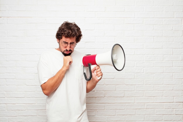 Jeune homme fou avec un mégaphone contre le mur de briques.