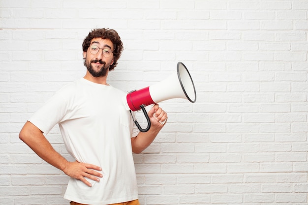 Jeune homme fou avec un mégaphone contre le mur de briques.