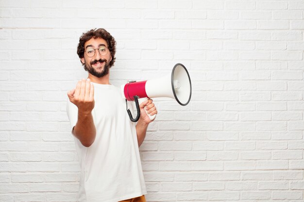 Jeune homme fou avec un mégaphone contre le mur de briques.