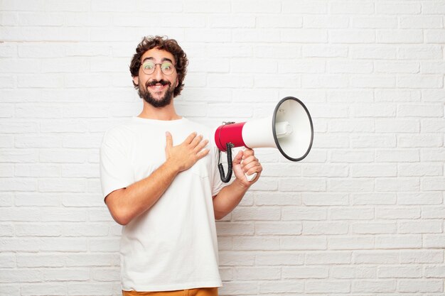 Jeune homme fou avec un mégaphone contre le mur de briques.