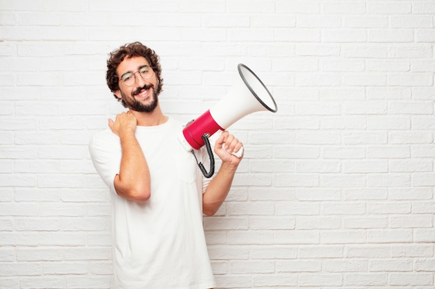 Jeune homme fou avec un mégaphone contre le mur de briques.